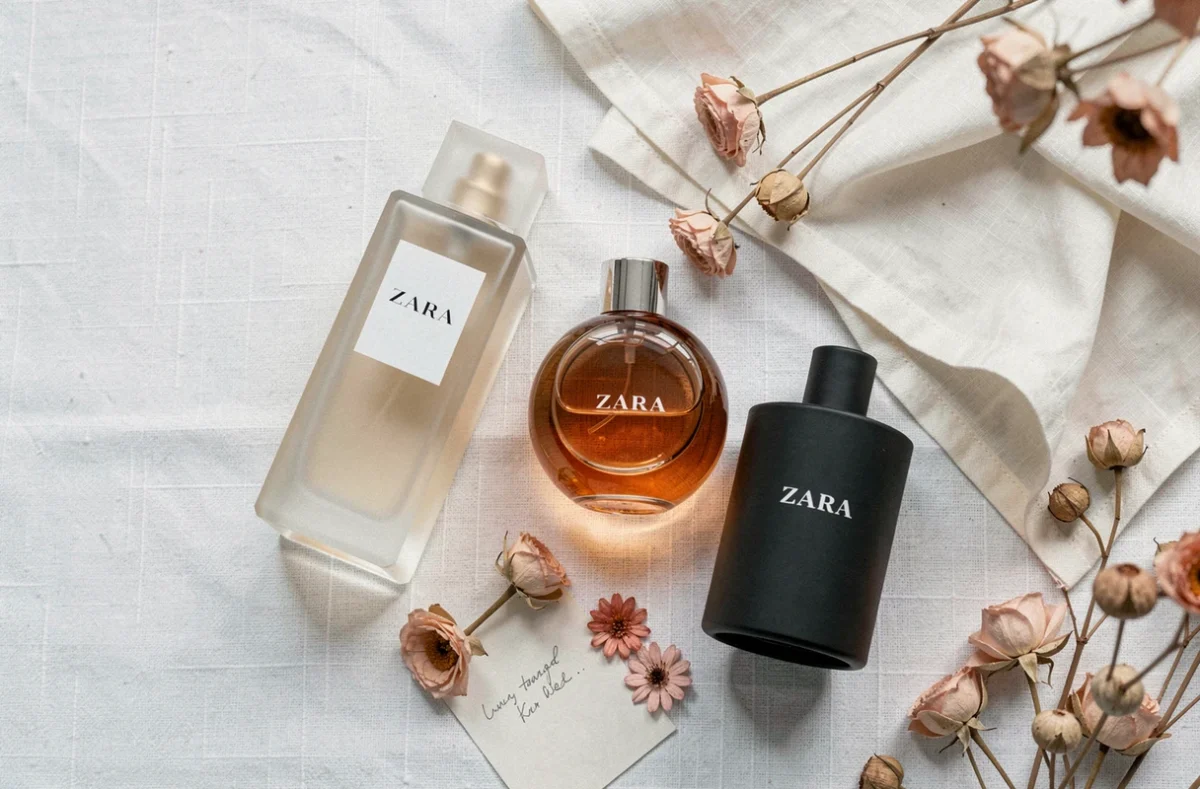 Flat-lay élégant de trois flacons de parfum Zara pour femme sur fond de lin blanc avec fleurs séchées