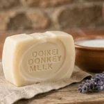 Savon artisanal au lait d'ânesse posé sur bois rustique avec bol de lait et lavande séchée